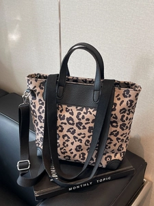 Leopard print canvas tote bag with black leather handles and adjustable nylon crossbody strap