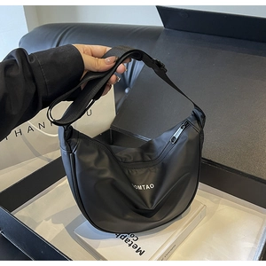 Détail d'un sac demi-lune en nylon noir avec bandoulière et logo imprimé