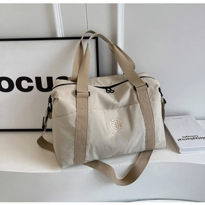 Détail du sac de voyage en nylon beige avec logo brodé et multiples poches de rangement