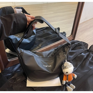 Détail du sac croissant en nylon noir avec bandoulière réglable et pendentif mascotte