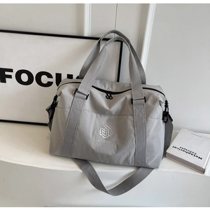 Gros plan de la broderie du logo NINGJIA sur le sac de voyage en nylon gris avec anses