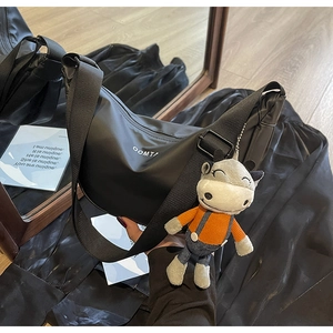 Détail du sac croissant en nylon noir avec logo OOMT et breloque en peluche vache
