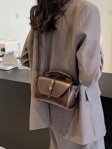 Retro dark brown crossbody box bag with metal buckle shown on a grey suit outfit
