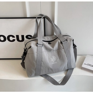 Détail d'un sac de voyage gris en nylon imperméable avec logo et poignées de transport
