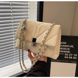Dettaglio borsa a tracolla in pelle beige con trapuntatura a V e catena metallica argento
