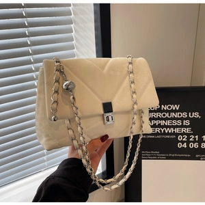 Dettaglio borsa trapuntata beige con cuciture a V e chiusura a girello argentata