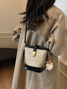 Beige emmertas met zwarte bies en pluche hanger gedragen door een vrouw