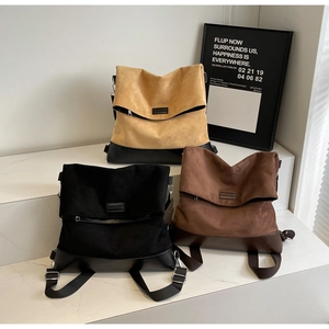 Three minimalist flap backpacks in black, brown, and yellow on marble steps