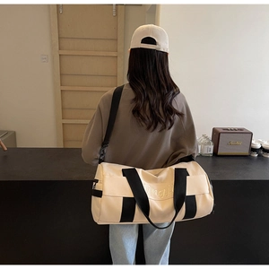 Close-up of cream canvas sports bag with black straps and Qingji embroidery detail