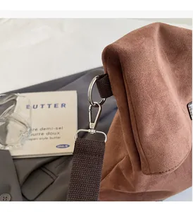 Detail view of premium silver swivel lock on brown suede shoulder bag with canvas strap