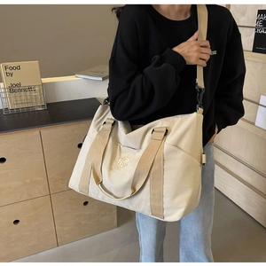 Vue latérale du sac fourre-tout beige en nylon avec large bandoulière sur un mannequin
