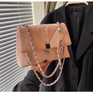 Borsa a tracolla rosa trapuntata con catena tenuta su uno sfondo di blazer nero