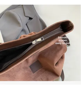 Detail view of the smooth silver metal zipper on the brown suede tote bag opening