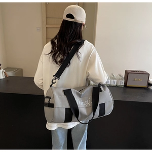 Rear view of a model carrying a grey fitness travel bag with shoulder strap and embroidery