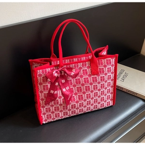 Detailed side view of a red wedding tote bag with Xi characters and a satin bow handle