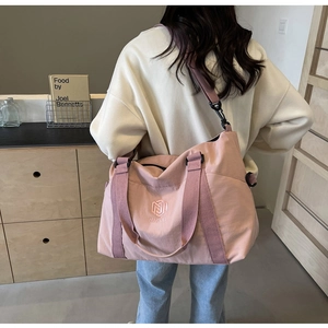 Vue détaillée du sac de voyage rose grande capacité avec logo brodé au dos