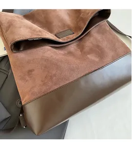 Detail of vintage brown suede and leather拼接 handbag with minimalist embossed logo