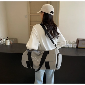 Detail of grey gym bag featuring a side zipper compartment and adjustable shoulder strap