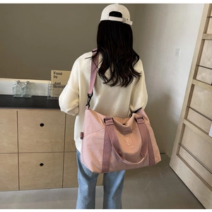 Détail du sac de voyage en nylon rose avec logo brodé et bandoulière amovible