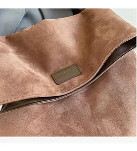 Detailed macro view of the brown suede texture and leather brand logo on a tote bag