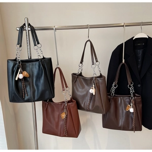 Detalle de bolsos tote elegantes en cuatro colores con cadena metálica y colgante de béisbol