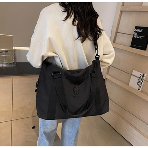 Détail d'un grand sac de voyage noir avec broderie MING MA et système de double sangle
