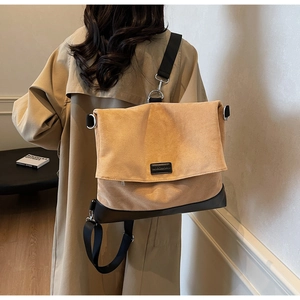 Detailed back view of khaki hobo bag with wide black strap on model in trench coat