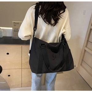 Grand sac de voyage en nylon noir avec bandoulière dans un cadre domestique