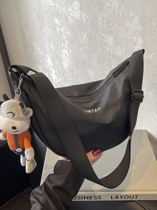 Sac bandoulière demi-lune en nylon noir tendance avec sangle et petit pendentif veau