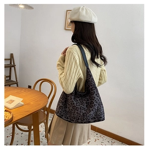 Detail of leopard print hobo bag showing wide black shoulder strap and soft fabric texture