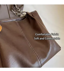 Primer plano del bolso tote de cuero marrón con costuras blancas y correa de cadena