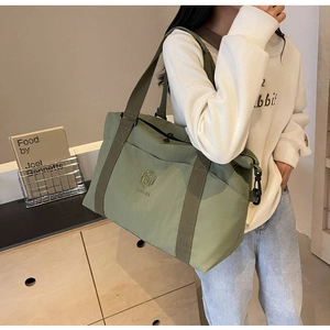 Détail du sac de voyage vert olive montrant le tissu durable et les crochets en métal