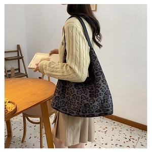 Close-up of leopard print tote bag with black leather strap worn by a model