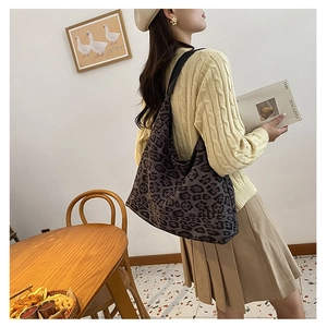 Close-up of leopard print tote bag with black leather straps on a fashion model