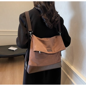 Close-up of caramel brown faux suede messenger bag with dark brown base and wide strap