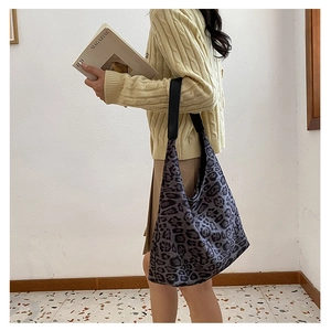 Detailed side view of large leopard print hobo bag worn by model in casual outfit