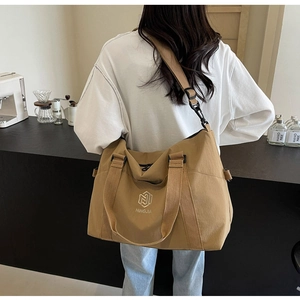 Vue arrière d'un mannequin portant le grand sac de voyage kaki avec logo de la marque