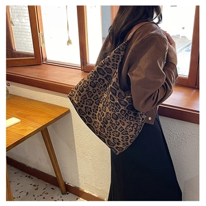 Macro detail of high-capacity leopard print tote bag with premium brown leather straps