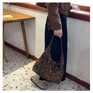 Detail of vintage leopard print tote bag with brown leather handles on wooden table