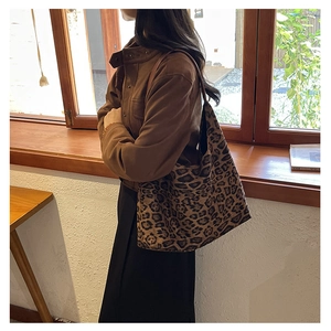 Detail of a large leopard print tote bag styled as a vintage shoulder bag on a model