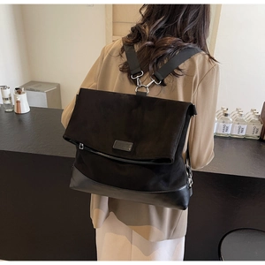 Detail view of the black flap backpack showing mixed textures and silver hardware buckles