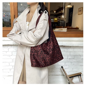 Detail of dark red leopard print tote bag styled with a beige trench coat in a cafe