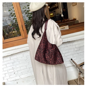 Detail of vintage red leopard print tote bag worn on shoulder in outdoor setting