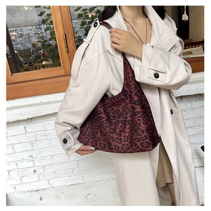 Fashionable leopard print tote bag in deep red carried by a model in an urban setting