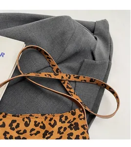 Dettaglio borsa a secchiello leopardata con tracolla in pelle marrone su sfondo grigio