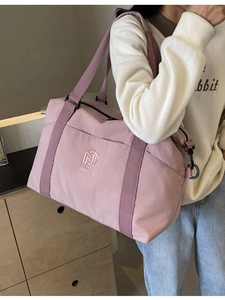 Grand sac de voyage imperméable rose pâle avec logo brodé porté en bandoulière ou à la main
