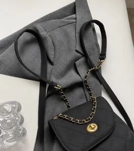Detail van de zwarte gewatteerde leertextuur met gouden ketting en draaisluiting