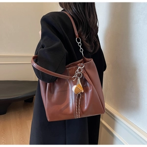 Bolso tote de cuero marrón con costuras en contraste y un colgante en la correa