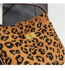 Dettaglio della chiusura a scatto dorata e della trama leopardata su borsa da donna
