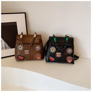 Detail of vintage backpacks with embroidered badges and woven rope handles in black and brown